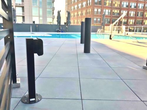 black outdoor power pedestal mounted by a residential pool
